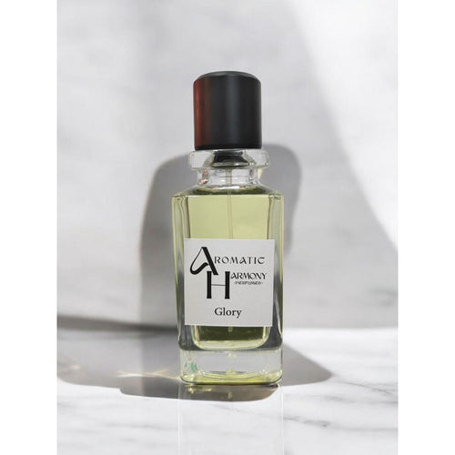 زجاجة عطر غلوري الشفافة بغطاء أسود وشعار متجر Aromatic Harmony